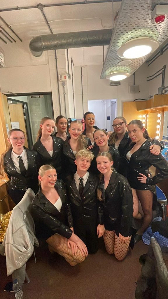 Dancers in shiny black costumes posing.