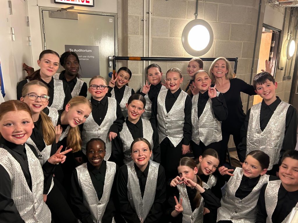 Group of performers in shiny outfits.