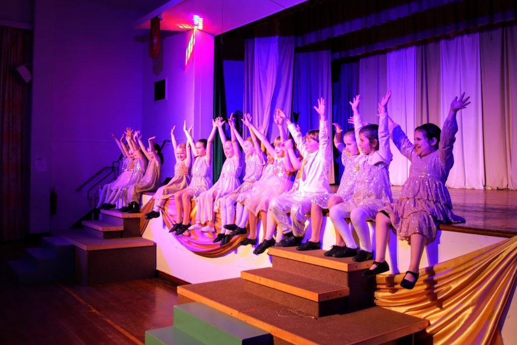 Children performing on stage with excitement.