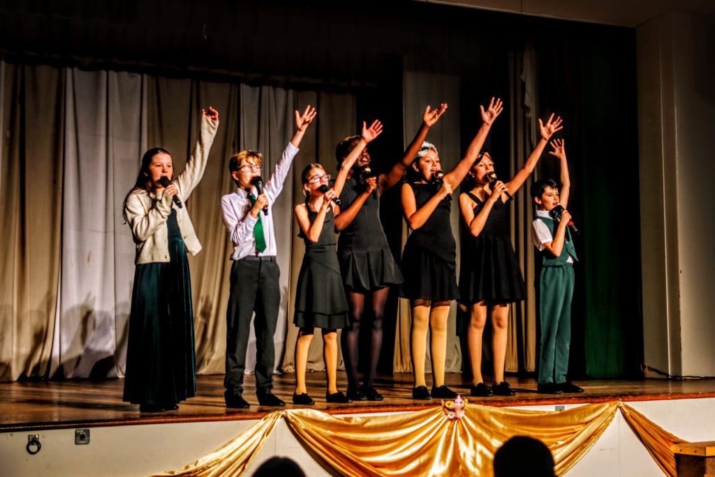 Group performing on stage, raising hands.