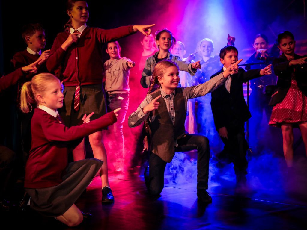 Children performing on stage with lights.