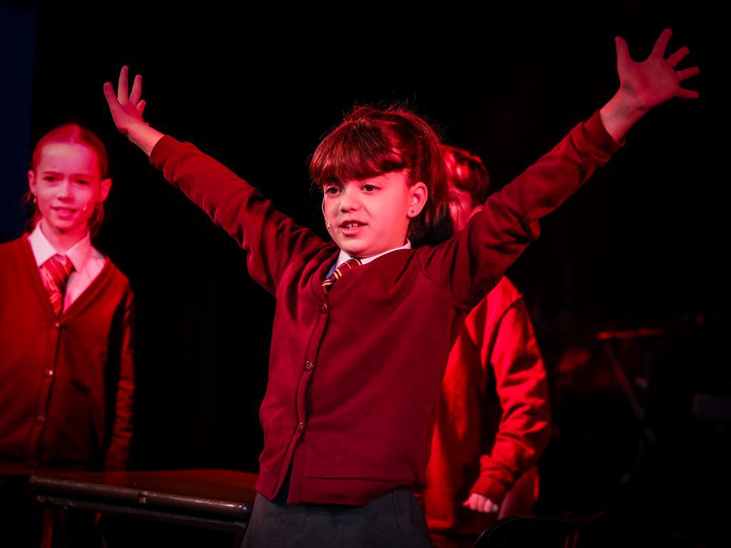 Children performing on stage, dramatic pose.