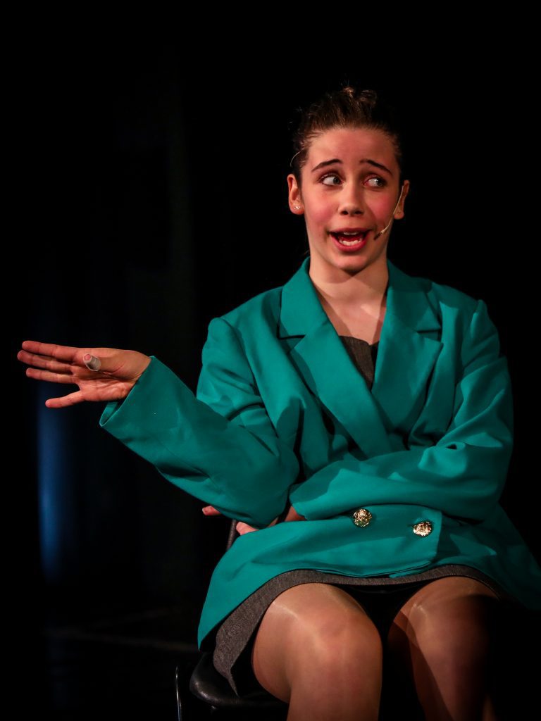 Person in teal jacket posing elegantly.