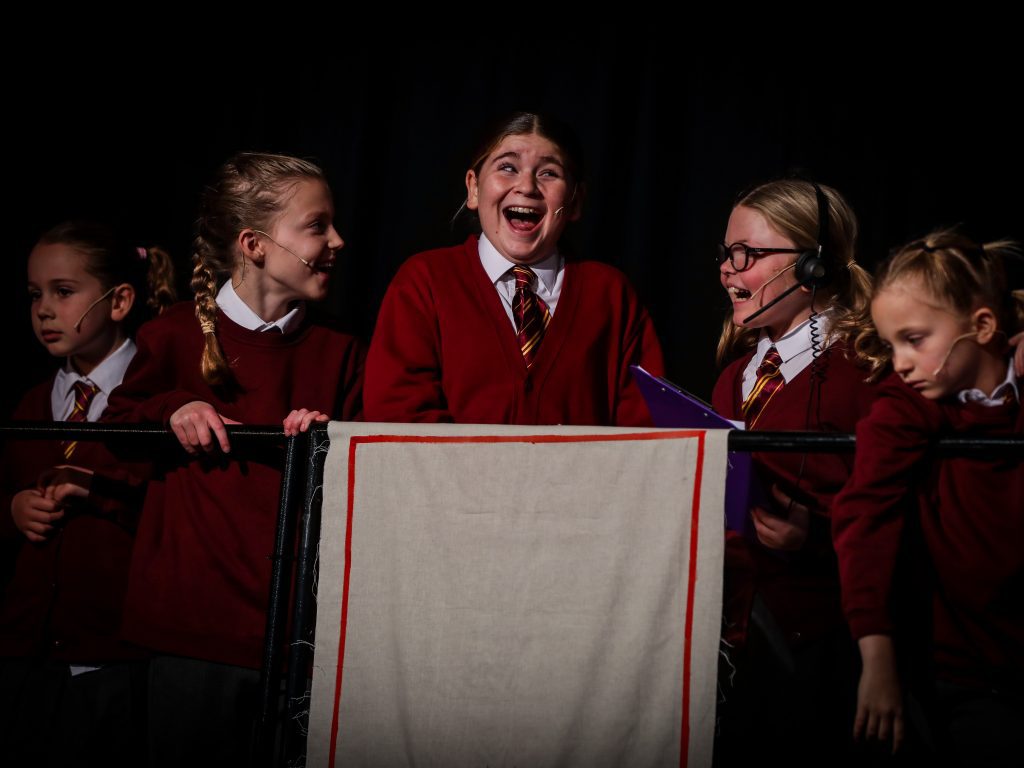 Students in red sweaters on stage.