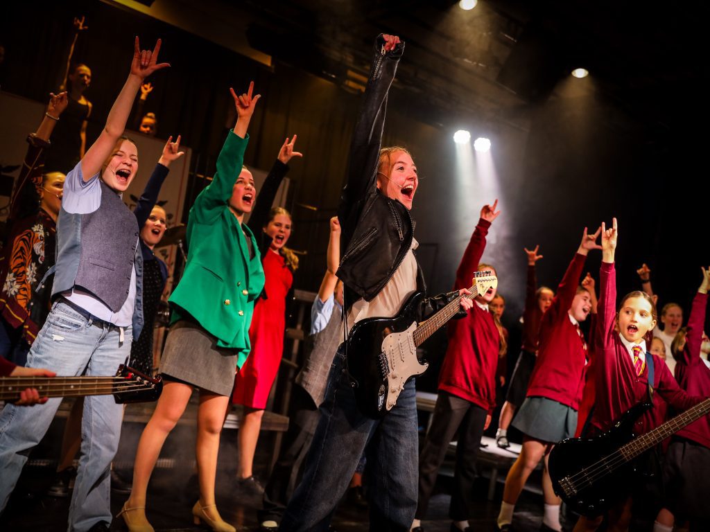 Group performing on stage with instruments.