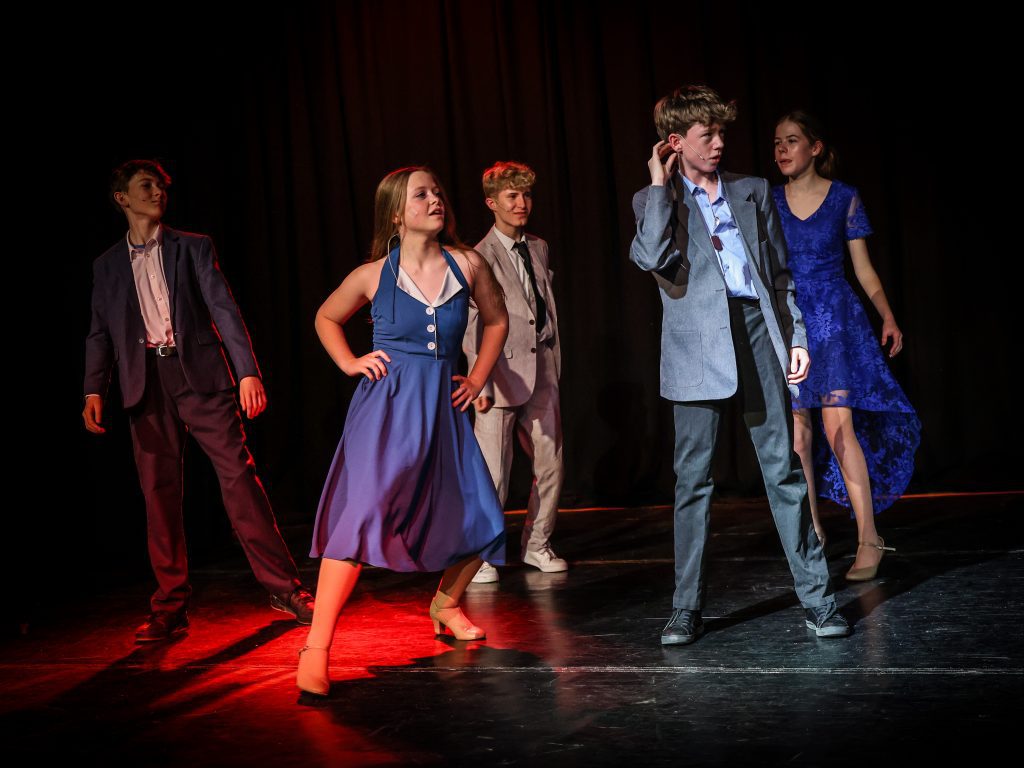 Children performing on stage in costumes.