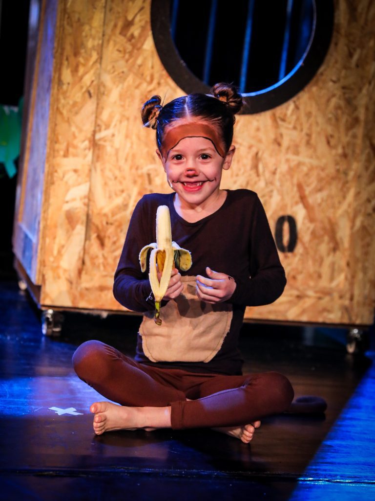 Child holding a banana on stage.