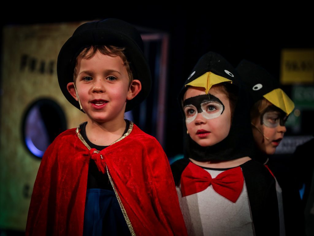 Children in costumes, one magician, penguins